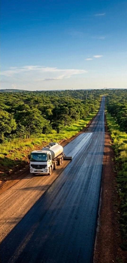 Road construction in progress — fresh tarmac being laid through Zambian bush